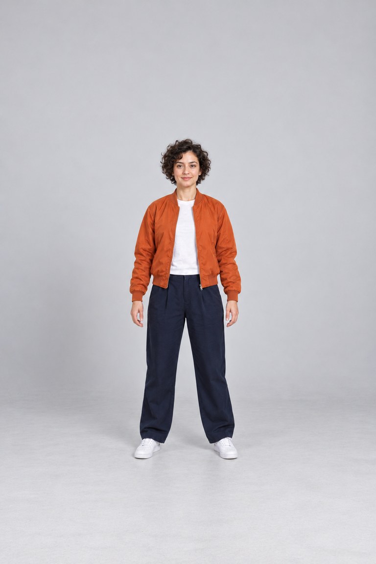 Full-body source photo of a fictional adult woman in an orange jacket, standing in a gray studio